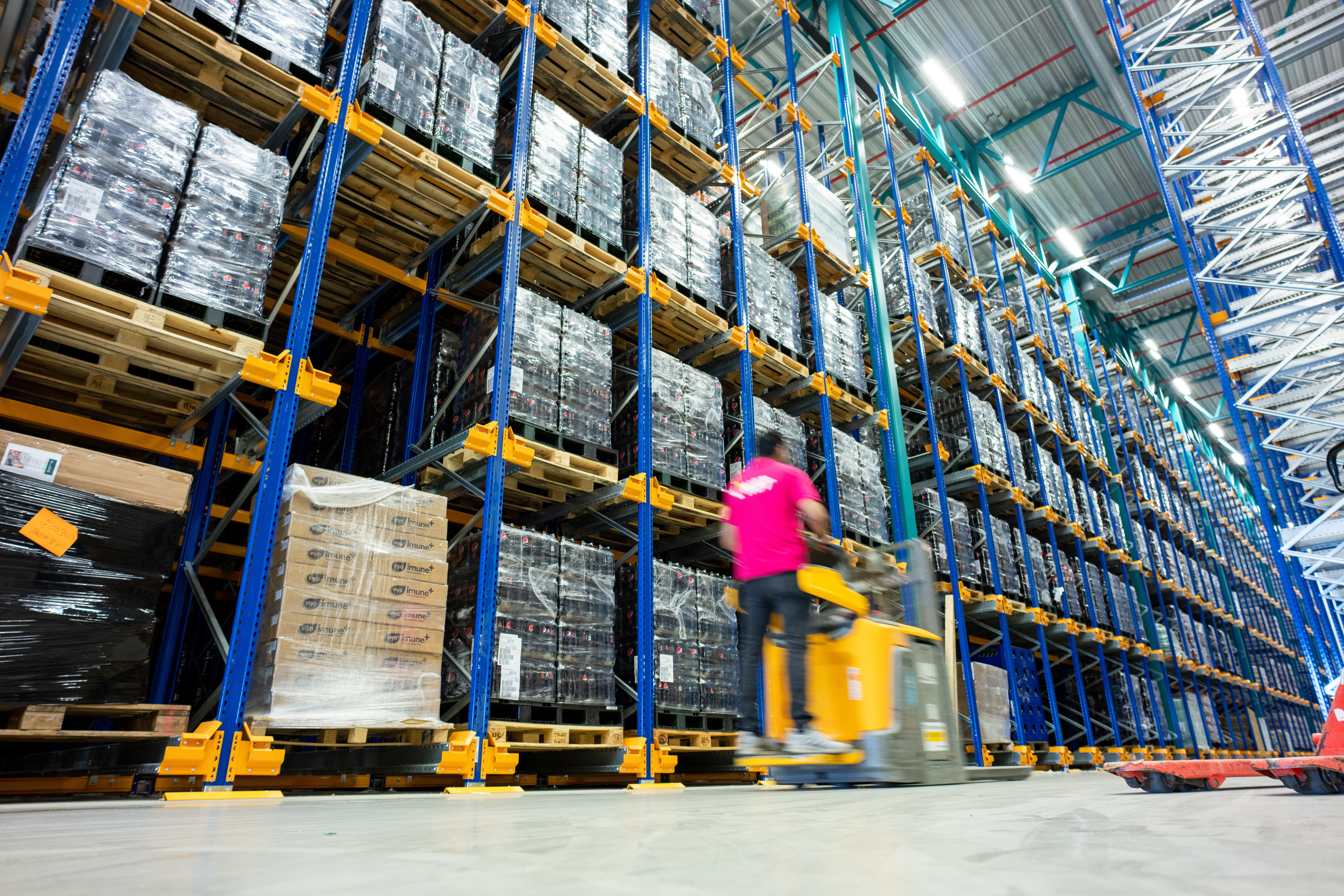 Fotografi av ansatt i arbeid på fullt pallelager.