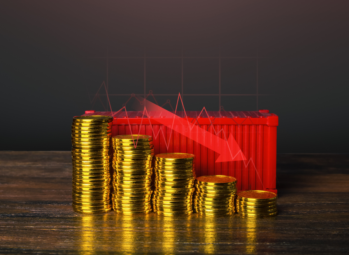 Bildet viser en bordmodell av en rød container og fire bunker med gullmynter i nedadgående sortering med en rød pil som beskriver reduserte kostnader. I betydningen reduserte fraktkostnader