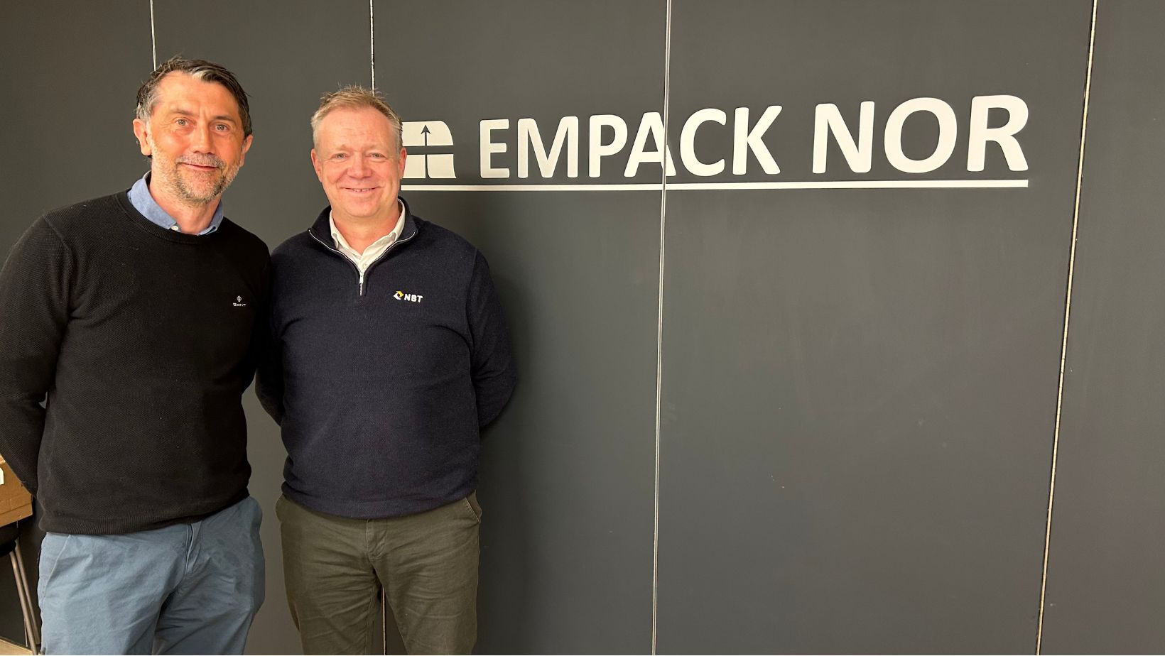 Fotografi av Thomas Dahl, daglig leder for Empack Nor, sammen med representant fra NBT. Empack Nor-logo i bakgrunn.