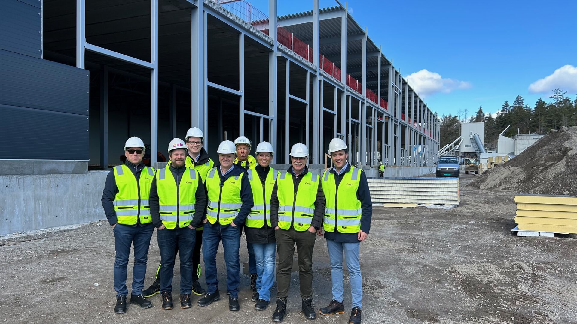 A group of people wearing security jackets and helmets in front of a construction building
