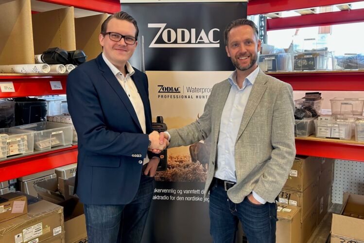 Fotografi av Rolf Ramberg, daglig leder for Zodiac Norge AS i et håndtrykk med KAM fra NBT. Zodiacs varelager og logo i bakgrunnen.